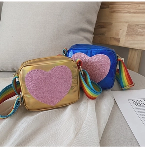 Détail de sacs bandoulière enfant en PU métallisé or et bleu avec cœur pailleté et sangle arc-en-ciel