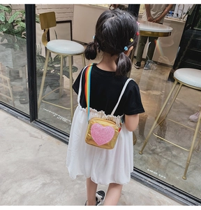 Détail d'un sac bandoulière doré avec cœur à paillettes et sangle arc-en-ciel pour enfant
