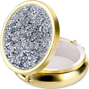 Macro detail of portable round gold pill box with diamond texture and three internal dividers