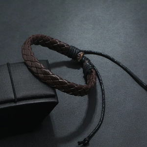 Close-up of dark brown woven leather bracelet with adjustable pull cord on a jewelry box