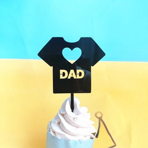 Detail shot of a black T-shirt shaped acrylic cupcake topper with gold DAD lettering