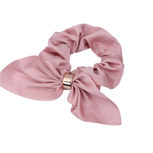 Pink satin rabbit ear hair tie with golden metal ring detail on a white background
