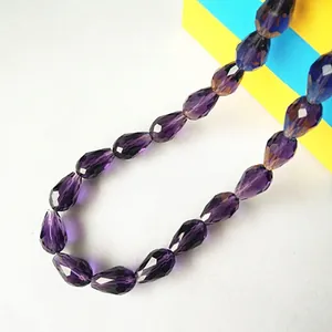 Close-up of faceted violet glass teardrop beads for DIY jewelry and decor projects