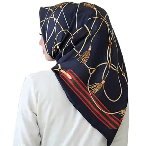 Close-up of silk scarf with gold chain print and signature red-green striped border