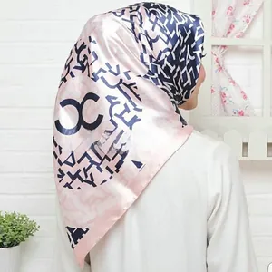 Detailed view of pink and navy satin square scarf with interlocking logo patterns