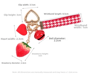 Detail of red strawberry keychain with dimensions showing heart charm and bell