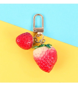 Detailed view of realistic strawberry keychain with gold hardware on vibrant background