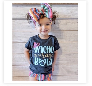 Close-up of baby t-shirt featuring Nacho Average Bow graphic with colorful striped shorts