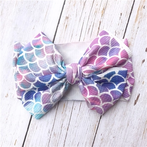 Detail view of baby headband with a large bow in gradient purple mermaid scale pattern