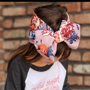 Close-up of a pink floral bow headband on a little girl with natural lighting