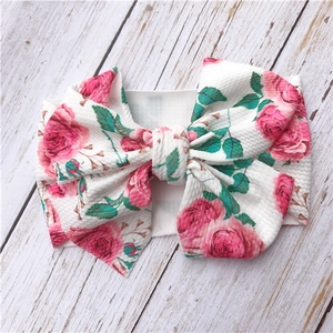 Close-up of white floral baby headband with pink roses and large knotted bow detail