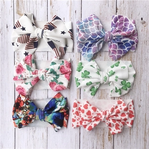 Detailed set of six patterned baby headbands with bows on a white wooden background