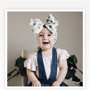Close-up of white baby headband with green shamrock print and large decorative bow