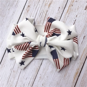 Close-up of white baby headband featuring USA flag pattern and large textured bow