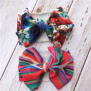Detail of floral and striped print baby headbands with large bows on light wood