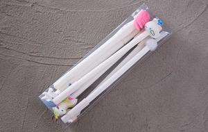 Close-up of six white cartoon gel pens with silicone toppers in a transparent box
