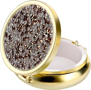 Detail of round gold metal pill box with sparkling rhinestone inlay and open lid