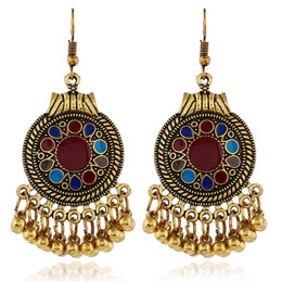 Detail of vintage gold-tone earrings with colorful enamel inlays and metallic bead fringe