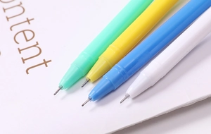 Close-up of four colorful plastic gel pens in green, yellow, blue, and white on paper