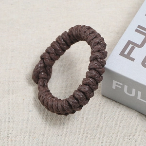 Gros plan d'un bracelet en corde tressée marron foncé sur fond de tissu texturé