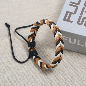 Macro shot of three-color braided couple bracelet with adjustable cord on fabric