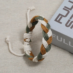 Detail of army green and coffee hand-woven cotton cord bracelet on fabric background