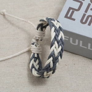 Detail of adjustable beige and grey hand-woven braided wax cord bracelet on burlap