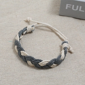 Detail of hand-woven bohemian bracelet featuring beige and dark grey braided cotton ropes