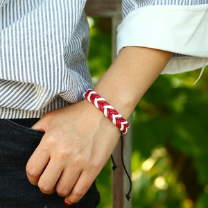 Handmade red and white woven bracelet for couples with adjustable black cord on wrist