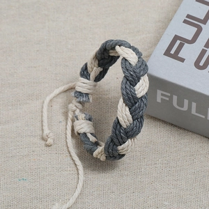 Close-up of handmade gray and beige woven rope bracelet with adjustable knot on canvas