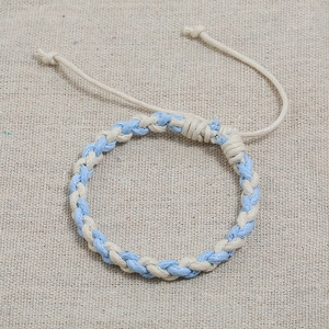 Close-up of hand-woven blue and white cord bracelet with adjustable drawstring design