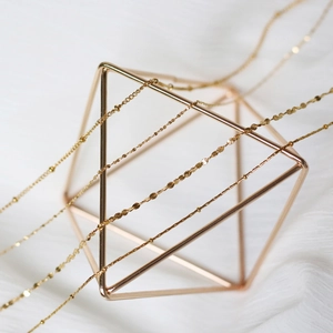 Multiple layered gold plated titanium steel necklaces displayed on a golden frame