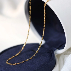 Macro shot of 18k gold plated petal chain necklace on a navy blue velvet jewelry box