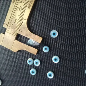 Macro shot showing measurement of a light blue mother of pearl Evil Eye shell bead
