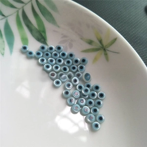 Flat round blue evil eye beads scattered on a white plate with leaf patterns