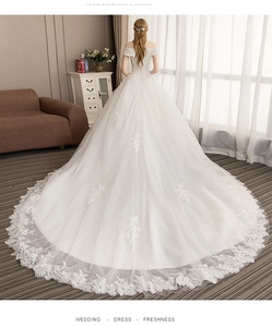 Detail of elegant off-the-shoulder wedding gown with lace train and lace-up back design