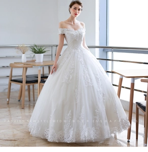 Detail view of the intricate lace embroidery and off-shoulder neckline on the white bridal gown