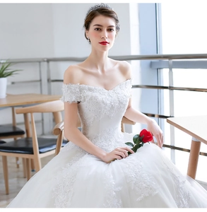 Detail view of white off-shoulder wedding dress with intricate lace floral embroidery