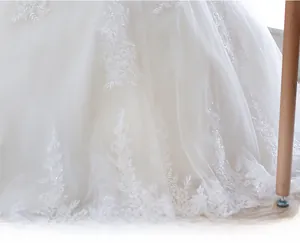 Detailed macro view of white lace floral embroidery on layered mesh wedding dress skirt