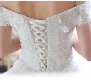 Detail of lace embroidery and adjustable corset tie back on white off-shoulder bridal gown
