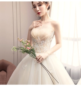 Detail of champagne bridal gown with floral lace bodice and layered tulle skirt