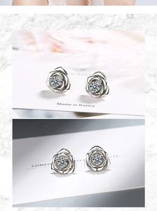 Macro detail of silver rose flower stud earrings with a clear central crystal inlay