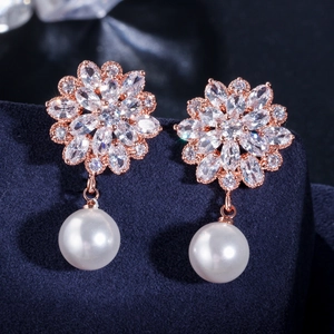 Macro shot of rose gold floral earrings with marquise zircons and white round pearls