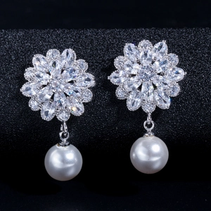 Detail of flower bridal earrings with zircon petals and hanging white round pearls