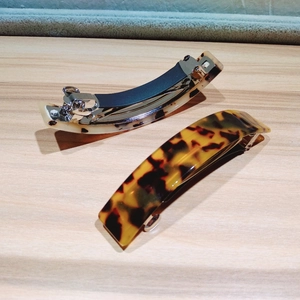 Detail of tortoise shell leopard hair clips with metal spring on wooden surface