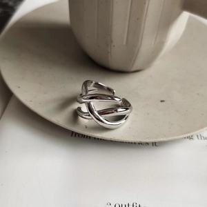Detailed view of an S925 sterling silver woven ring on a ceramic plate with a book