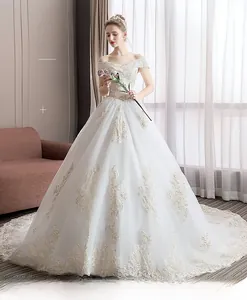 Detail of off-shoulder wedding dress with intricate gold lace embroidery and long train