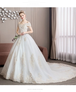 Detailed close-up of intricate gold lace embroidery on a white off-shoulder bridal gown