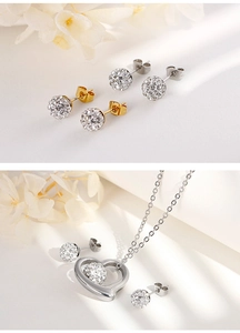 Detail of silver hollow heart pendant and crystal ball earrings set on white surface