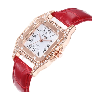 Detail of square rose gold watch case with crystal bezel and red crocodile leather strap